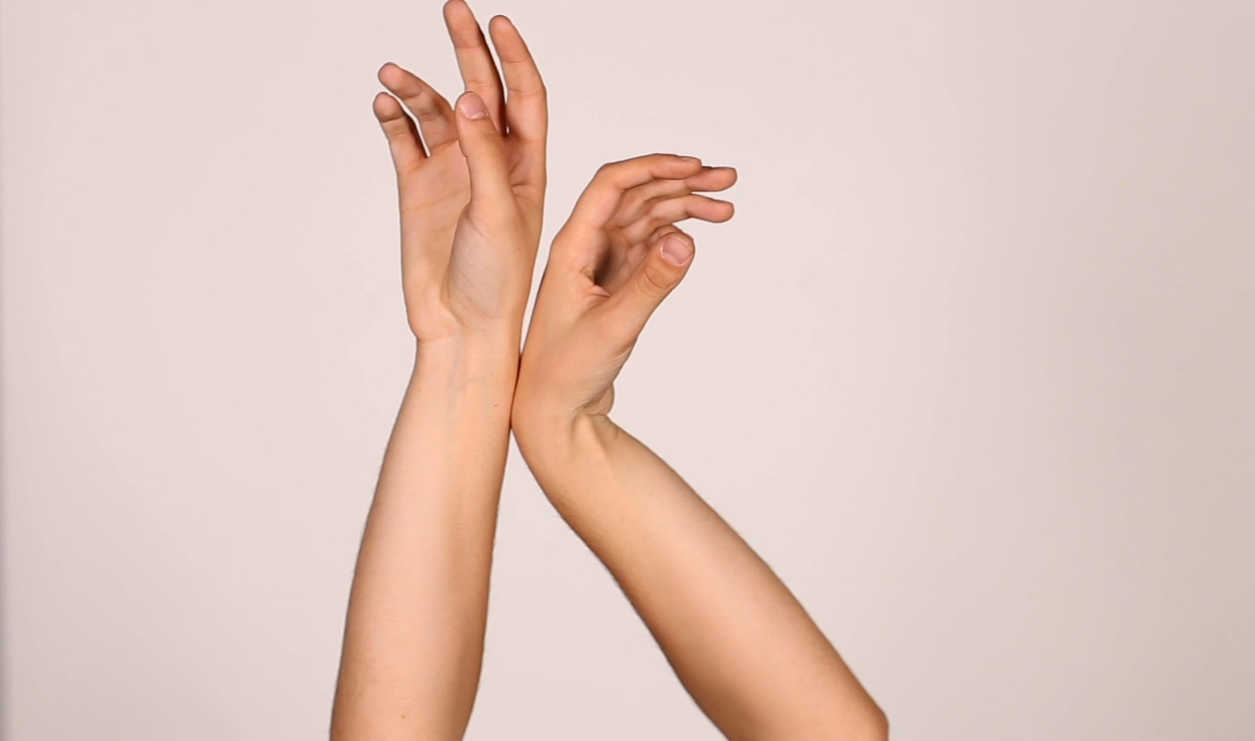 two arms touching at the wrists against a plain background